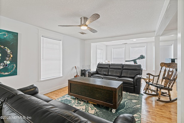 living room featuring light hardwood / wood-style floors, a textured ceiling, ceiling fan, and a healthy amount of sunlight