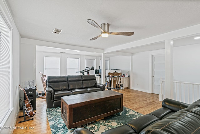 living room with a textured ceiling, ceiling fan, and light hardwood / wood-style floors