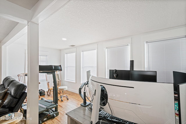 workout area with a textured ceiling and light hardwood / wood-style flooring