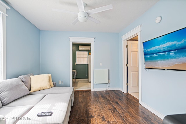 living room featuring ceiling fan, dark hardwood / wood-style flooring, and a wall unit AC