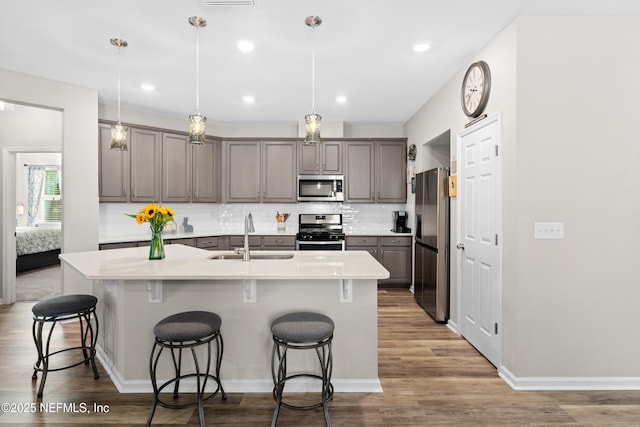 kitchen featuring pendant lighting, stainless steel appliances, sink, backsplash, and a breakfast bar area