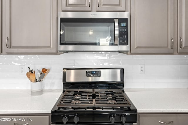 kitchen featuring light stone counters, backsplash, and gas stove