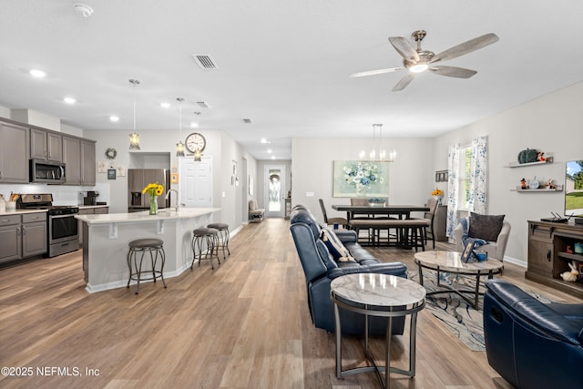 living room featuring light wood-type flooring and ceiling fan with notable chandelier