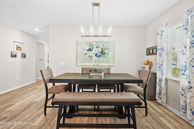 dining area with light hardwood / wood-style flooring and a notable chandelier