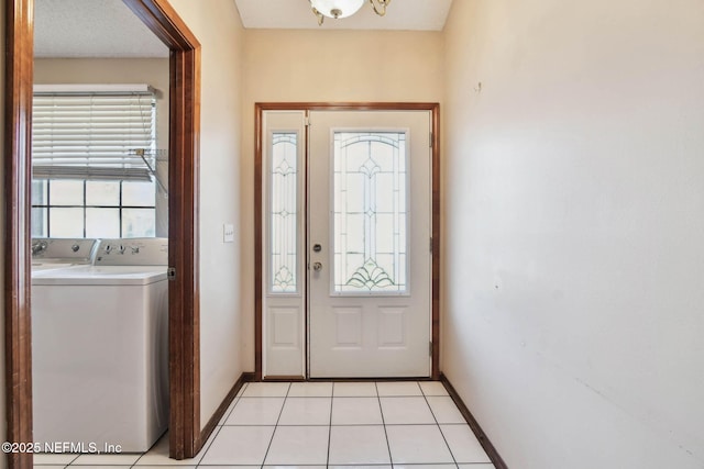 doorway with washing machine and clothes dryer and light tile patterned flooring