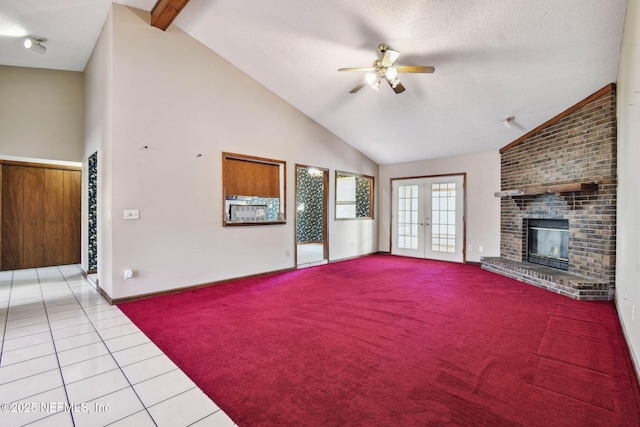 unfurnished living room featuring light tile patterned floors, ceiling fan, a fireplace, french doors, and beam ceiling