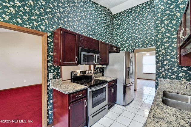 kitchen with light stone countertops, light tile patterned floors, stainless steel appliances, and sink