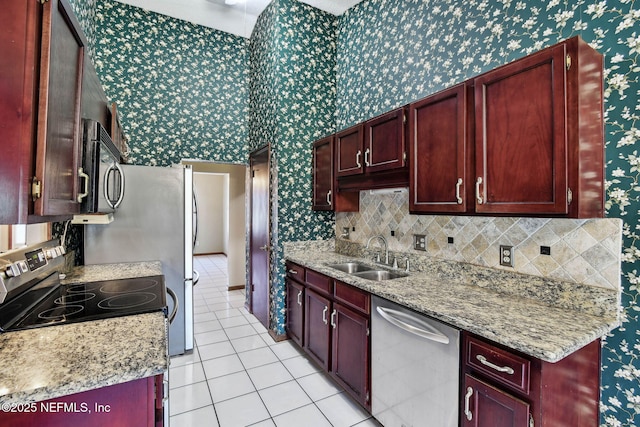 kitchen featuring appliances with stainless steel finishes, tasteful backsplash, light tile patterned flooring, light stone counters, and sink