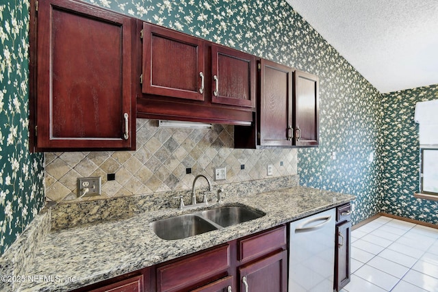 kitchen with stainless steel dishwasher, light stone countertops, sink, and light tile patterned flooring