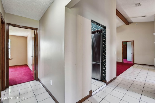 corridor with a textured ceiling, light tile patterned flooring, and vaulted ceiling with beams