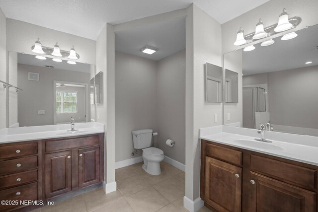 bathroom featuring a shower with shower door, tile patterned floors, vanity, and toilet