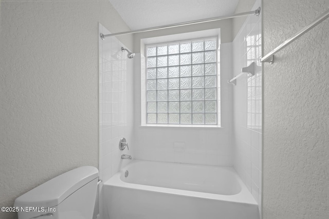 bathroom featuring toilet, tiled shower / bath, and a wealth of natural light