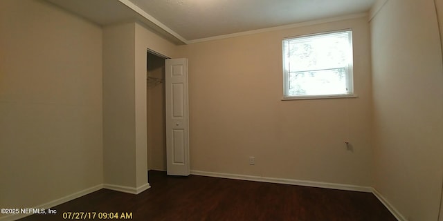 unfurnished bedroom with a closet, dark hardwood / wood-style flooring, and crown molding