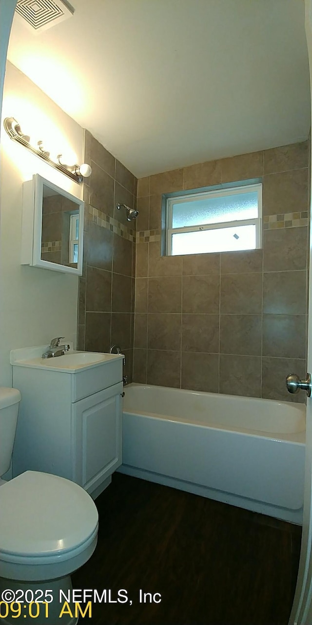 full bathroom with toilet, tiled shower / bath, and vanity