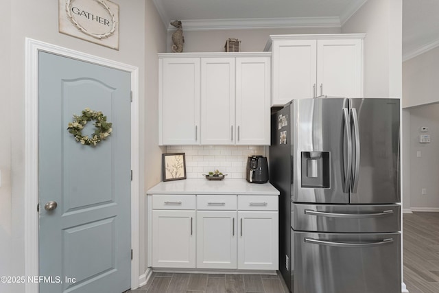 kitchen with backsplash, white cabinetry, crown molding, and stainless steel refrigerator with ice dispenser