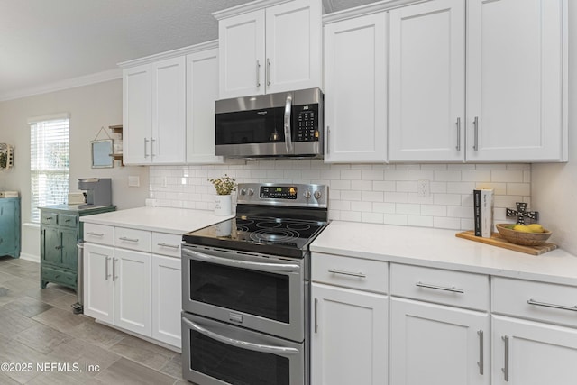 kitchen with backsplash, crown molding, white cabinets, and stainless steel appliances