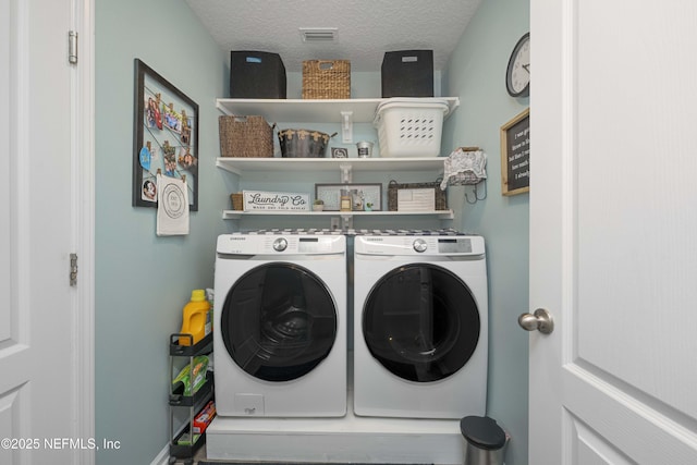 laundry room featuring a textured ceiling and washer and dryer