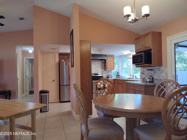 kitchen featuring wall chimney range hood, lofted ceiling, stainless steel appliances, and tasteful backsplash