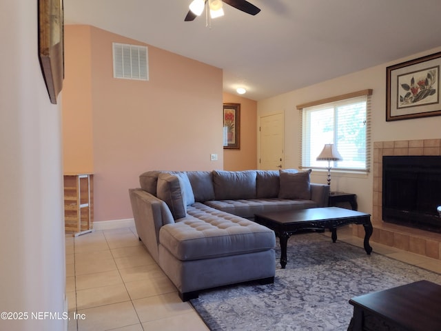 living room with ceiling fan, a fireplace, lofted ceiling, and light tile patterned flooring