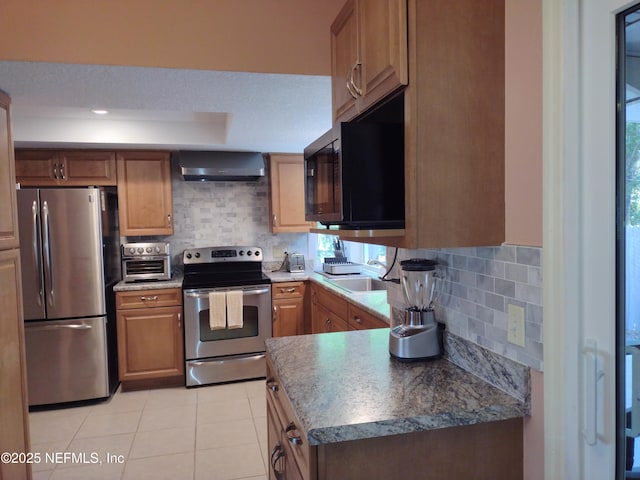 kitchen featuring stainless steel appliances, wall chimney exhaust hood, tasteful backsplash, and sink