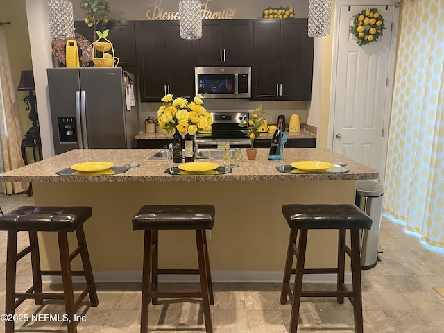 kitchen with a breakfast bar area, stainless steel appliances, and a kitchen island with sink