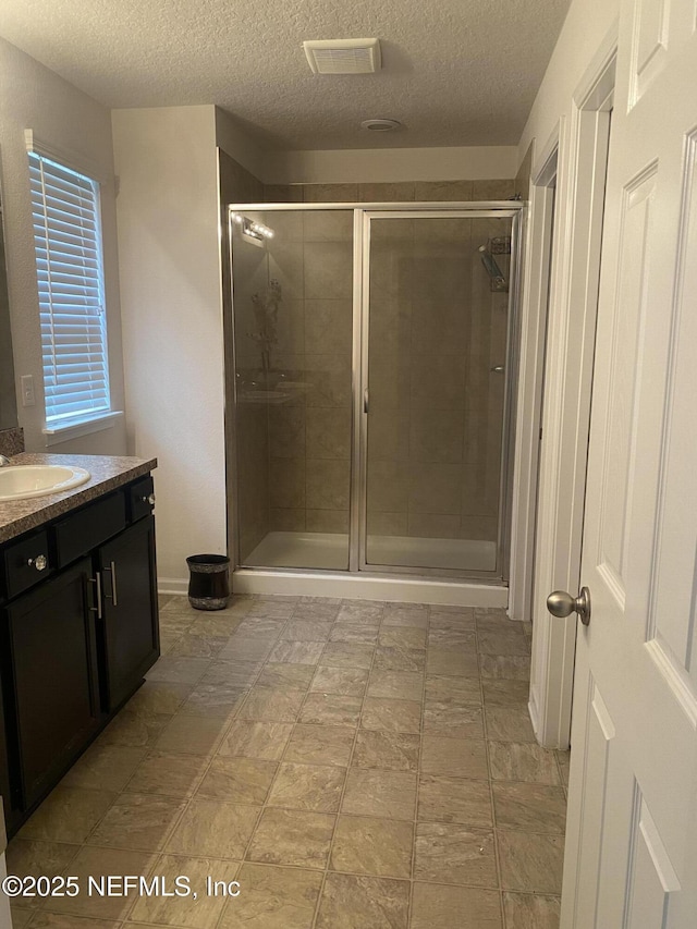 bathroom featuring vanity, a textured ceiling, and an enclosed shower