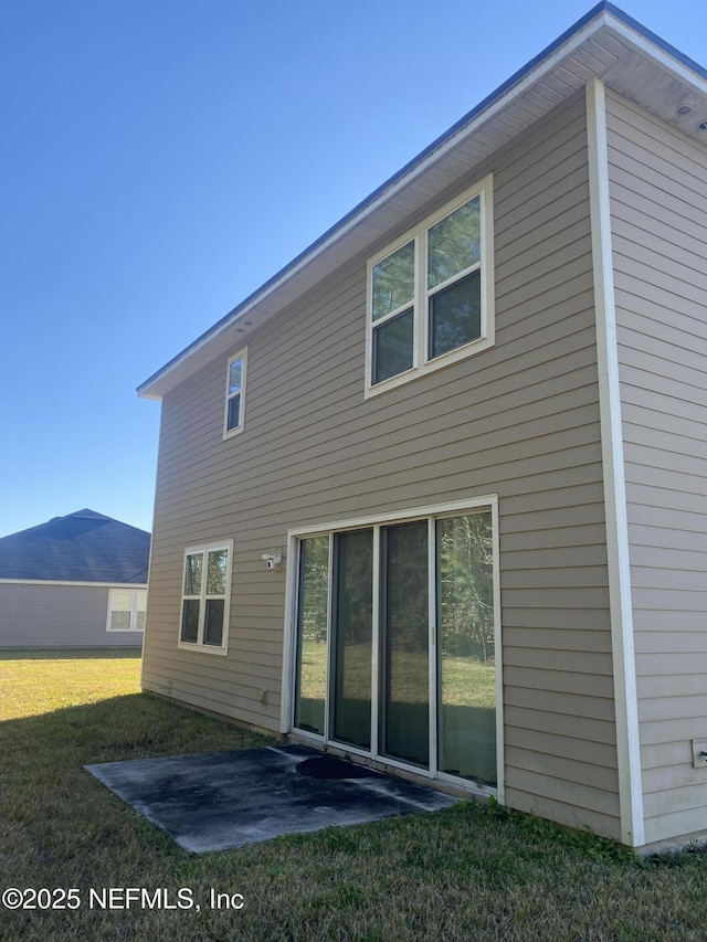 back of house with a lawn and a patio