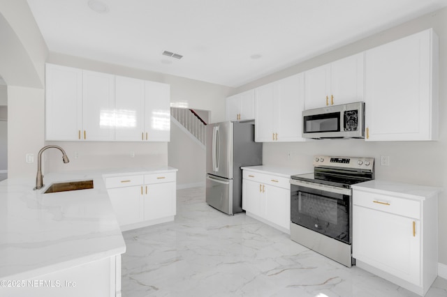 kitchen with appliances with stainless steel finishes, white cabinets, and sink