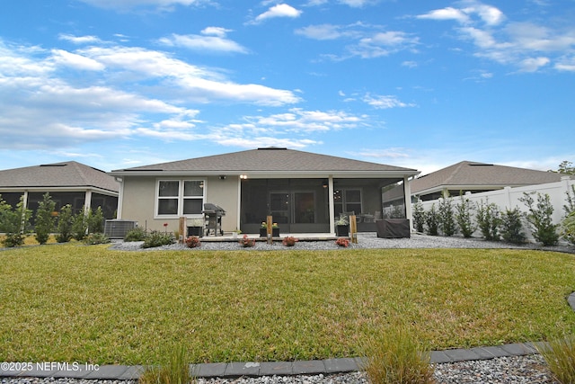 back of property with a sunroom, a lawn, and central air condition unit