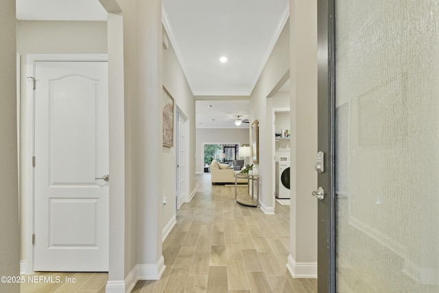 corridor featuring washer / dryer, ornamental molding, and light hardwood / wood-style flooring