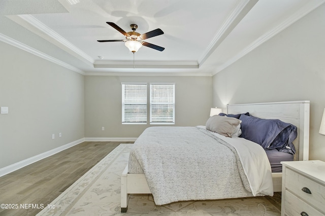 bedroom featuring ceiling fan, ornamental molding, light hardwood / wood-style flooring, and a raised ceiling