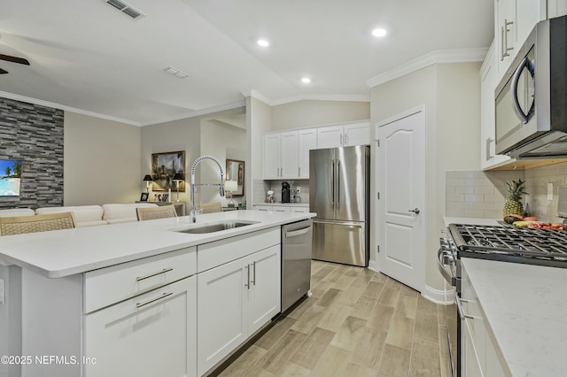 kitchen with sink, white cabinets, appliances with stainless steel finishes, and vaulted ceiling