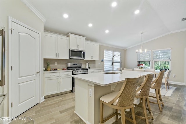 kitchen with sink, white cabinets, appliances with stainless steel finishes, and an island with sink