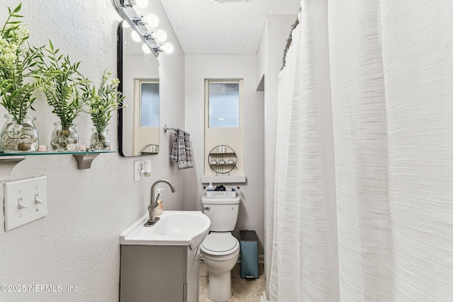 bathroom featuring vanity, toilet, and a textured ceiling