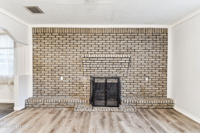 unfurnished living room featuring crown molding, a fireplace, hardwood / wood-style floors, and a textured ceiling