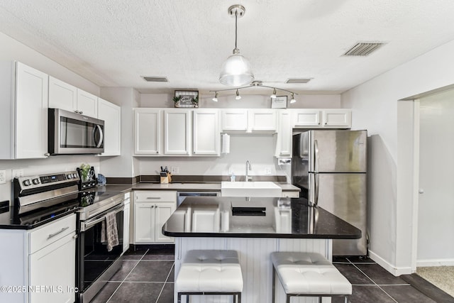 kitchen featuring white cabinetry, a kitchen bar, decorative light fixtures, and appliances with stainless steel finishes