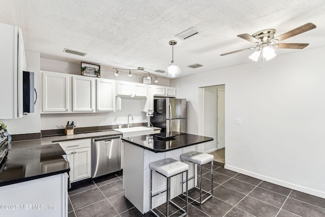 kitchen with sink, white cabinetry, a center island, hanging light fixtures, and appliances with stainless steel finishes