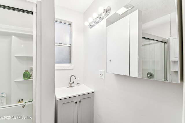 bathroom with vanity, a shower with door, and a textured ceiling