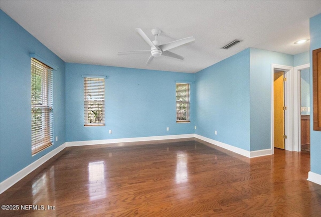 empty room with ceiling fan and dark hardwood / wood-style flooring