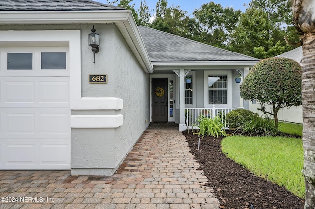 doorway to property featuring a garage and a porch