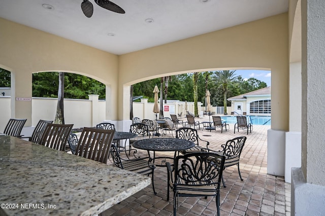 view of patio featuring ceiling fan and a community pool