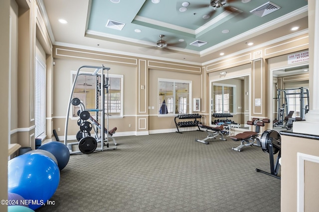 gym with a raised ceiling, ceiling fan, carpet floors, and ornamental molding