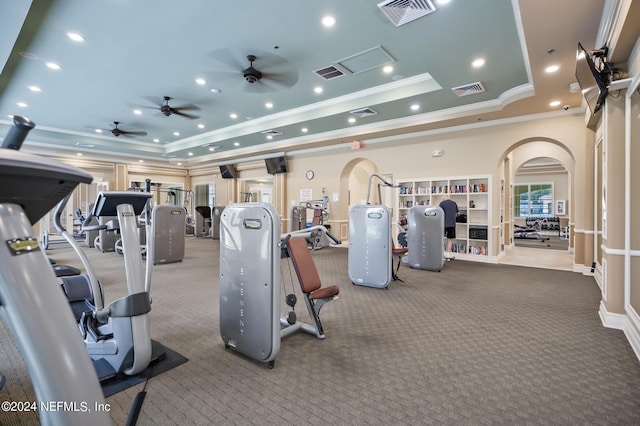 gym featuring ceiling fan, ornamental molding, carpet, and a tray ceiling