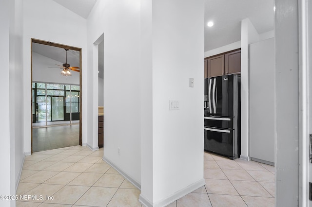 hallway featuring vaulted ceiling and light tile patterned flooring