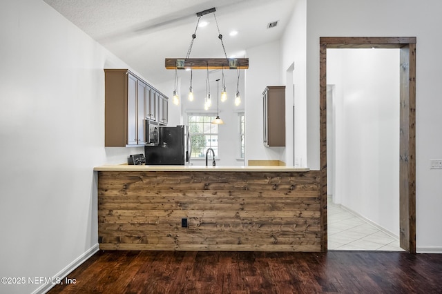 kitchen featuring kitchen peninsula, hardwood / wood-style floors, decorative light fixtures, stainless steel refrigerator, and a textured ceiling