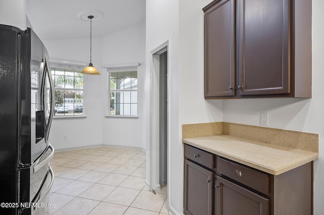 kitchen featuring hanging light fixtures, dark brown cabinetry, black fridge, and light tile patterned flooring