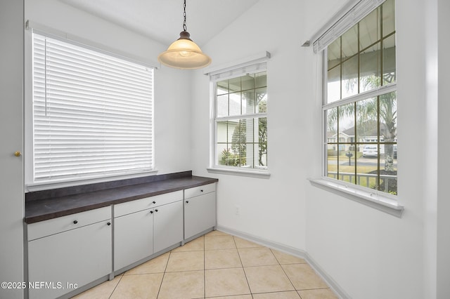 unfurnished dining area with vaulted ceiling and light tile patterned flooring