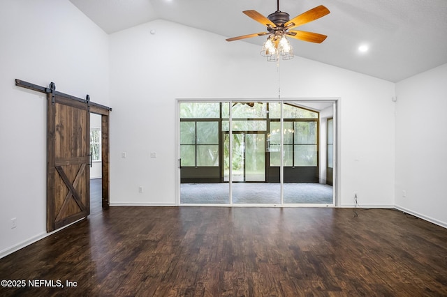 spare room with ceiling fan, dark wood-type flooring, a barn door, and vaulted ceiling