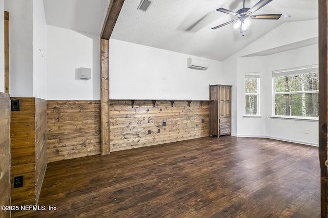 unfurnished room featuring a textured ceiling, dark wood-type flooring, lofted ceiling with beams, a wall mounted AC, and ceiling fan