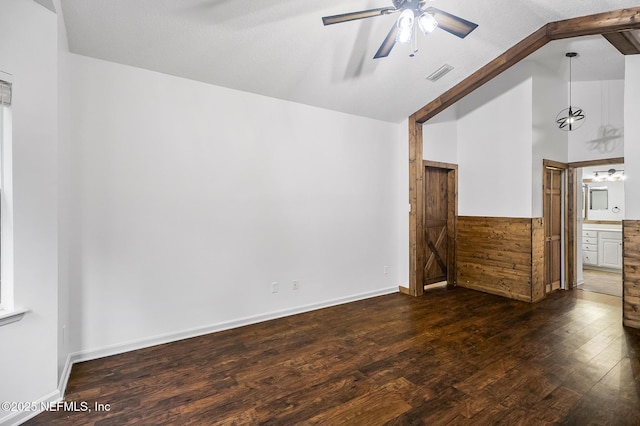 unfurnished living room featuring ceiling fan, lofted ceiling with beams, dark hardwood / wood-style floors, and wood walls